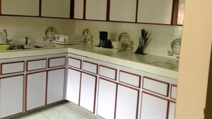 Cuina amb armaris blancs i una paret verda.
