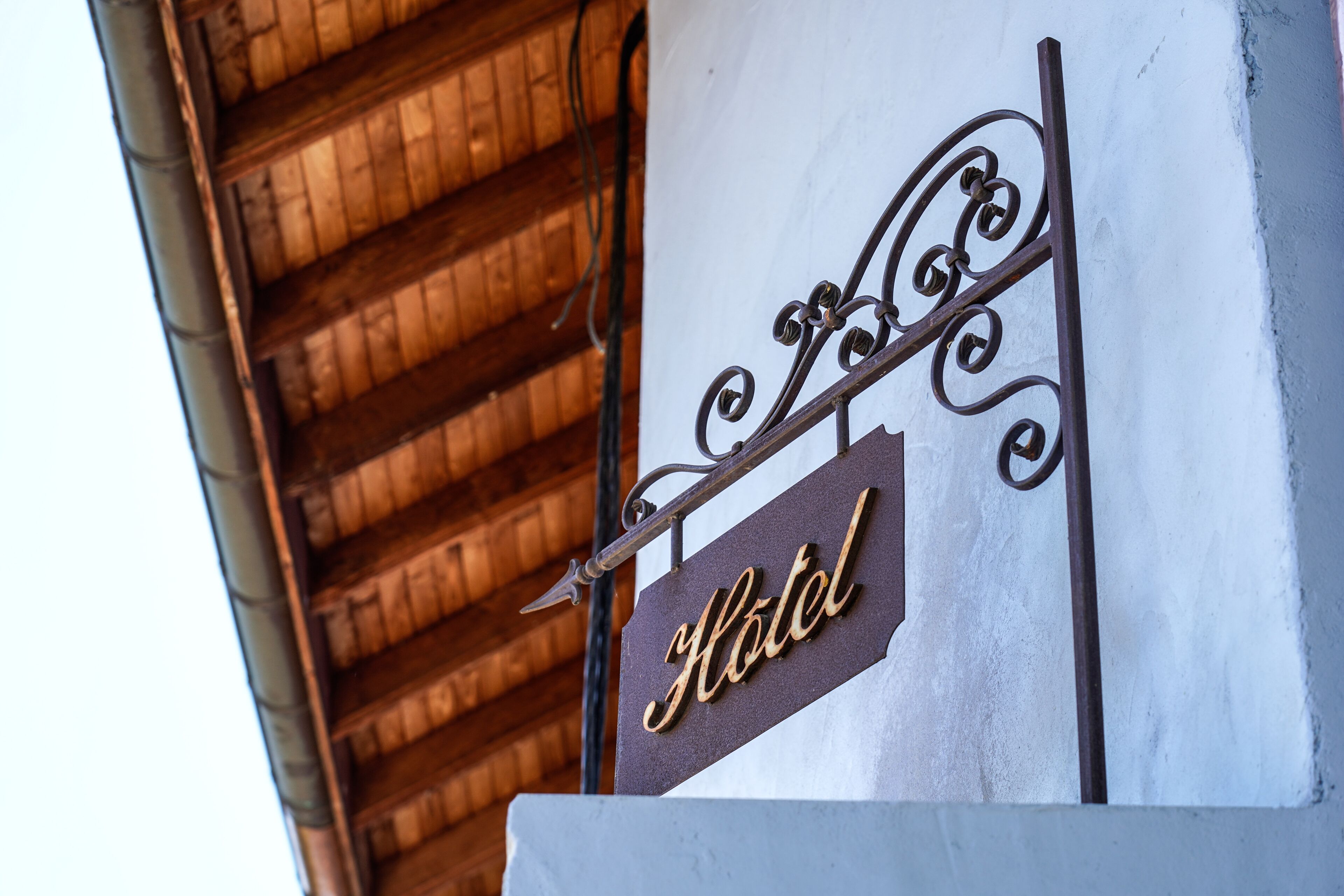 Een hotelschilderij met een sierlijk ijzeren ontwerp en het woord 'Hotel' in sierletters op een witte achtergrond.