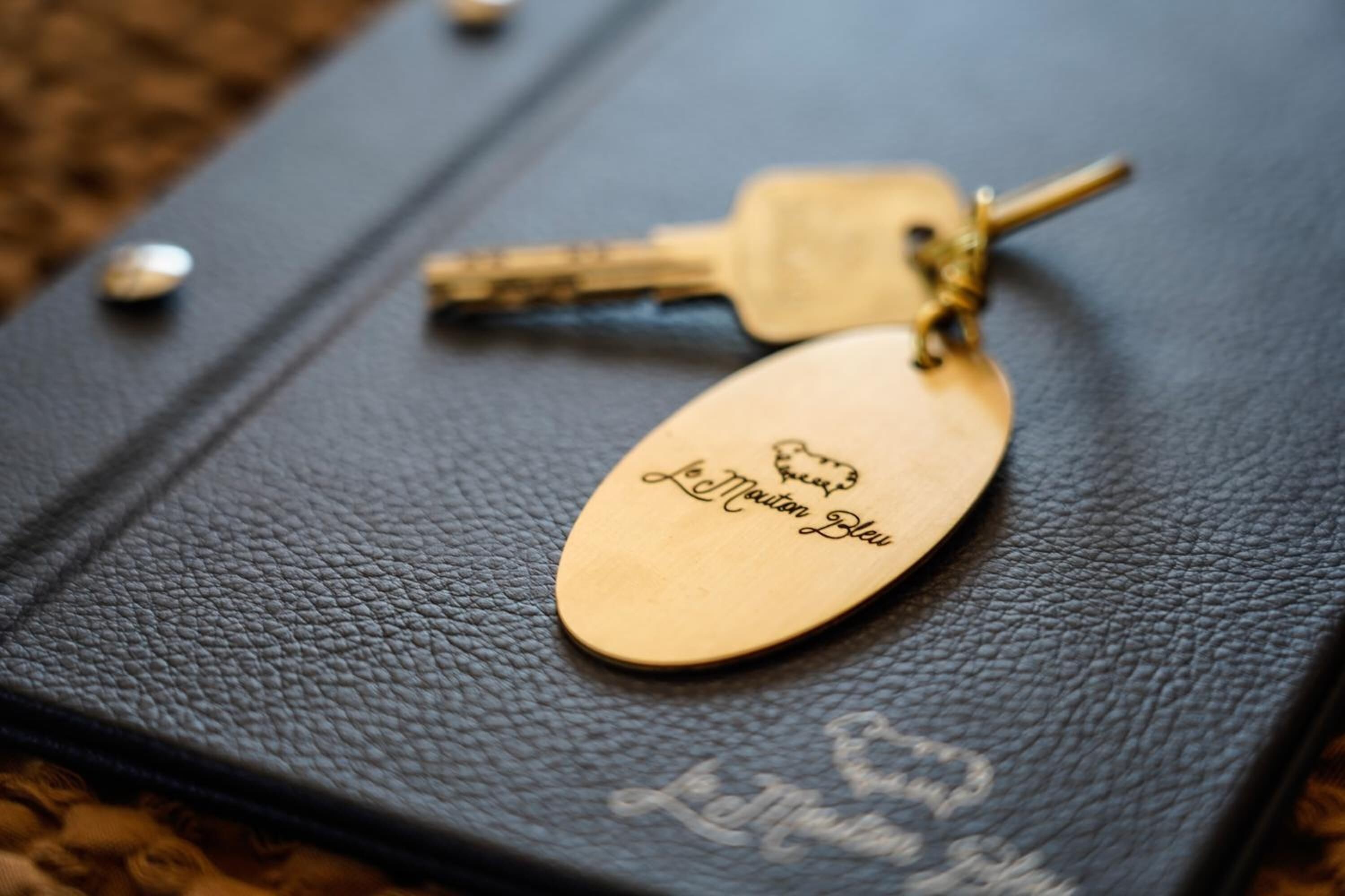 A black leather-bound book with keys and a gold tag on it.