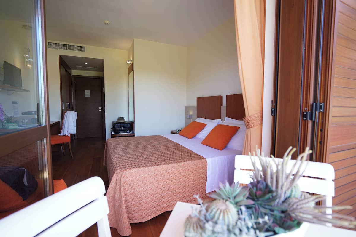 Une chambre d’hôtel avec un lit, une chaise, une table et une plante.