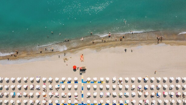 An aerial view of a beach with rows of beach umbrellas and sun loungers.