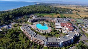 An aerial view of a resort with a central swimming pool, multiple buildings, and surrounding greenery.