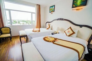 Een hotelkamer met twee bedden, een stoel en een groot raam met uitzicht op de stad.