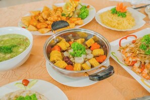 Ein Tisch mit verschiedenen Speisen, darunter eine Schüssel Mais mit Gemüse und eine Portion frittierter Gerichte.