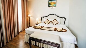 Quarto de hotel com cama bem arrumada, luminária de cabeceira e um quadro na parede.