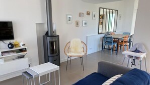 Ein modernes Wohnzimmer mit einer Couch, einem Fernseher, einem Kamin und einem Essbereich mit Stühlen und einem Tisch.