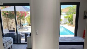 Ein modernes Schlafzimmer mit einem großen Schiebeglasfenster, das auf eine Terrassenfläche führt.