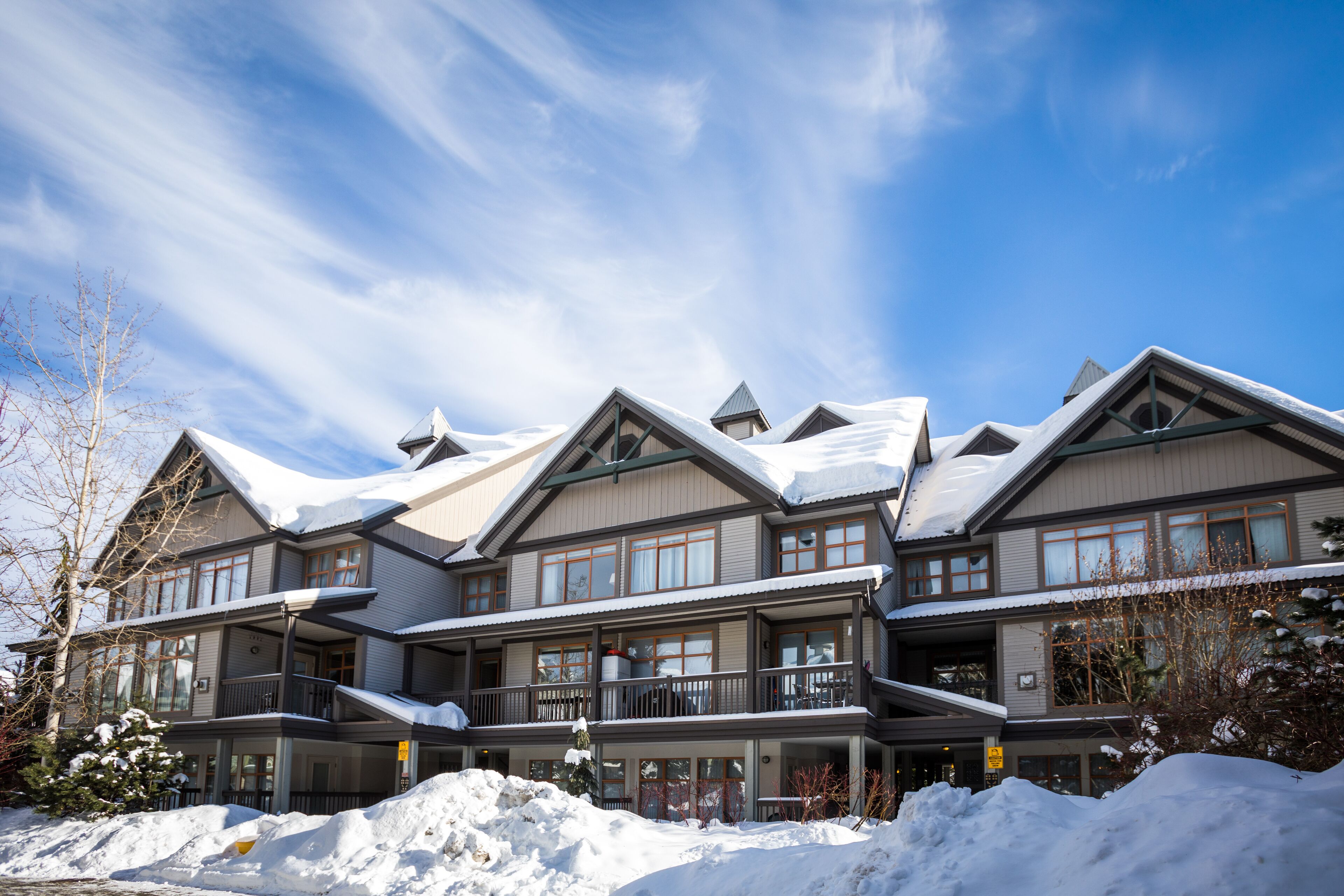 Un hôtel à plusieurs étages, doté de balcons et de grandes fenêtres, et entouré de neige.