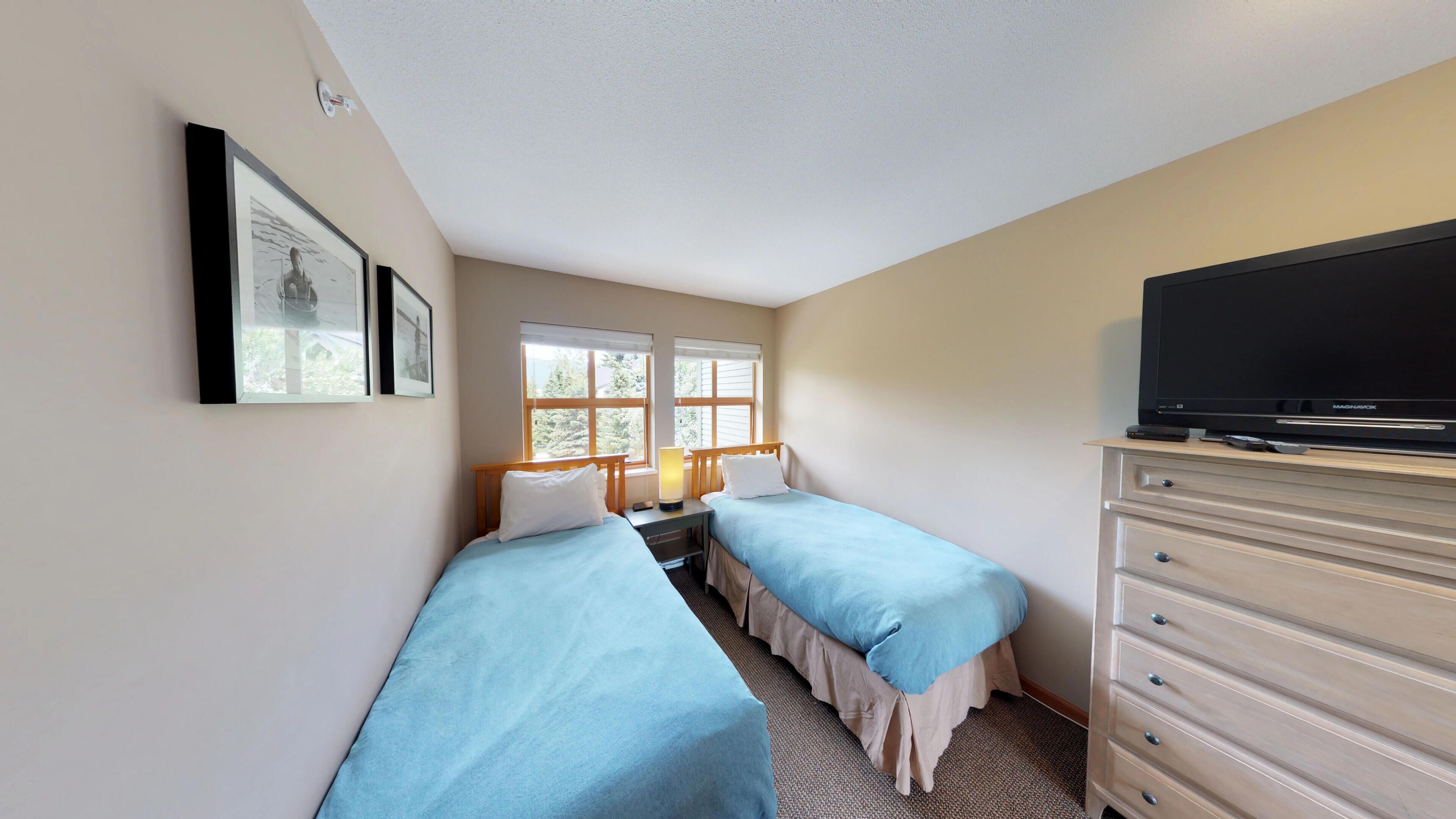 A hotel room with two beds, a television, and a dresser.