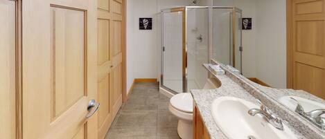 A modern bathroom with wooden cabinets, a shower, a toilet, and a large mirror.