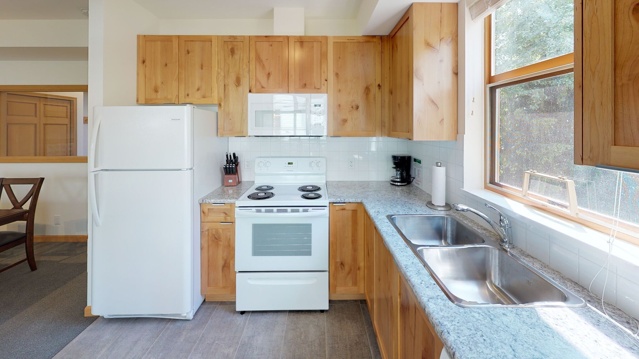 Une cuisine avec des meubles de rangement en bois, un réfrigérateur blanc, une cuisinière et un évier.