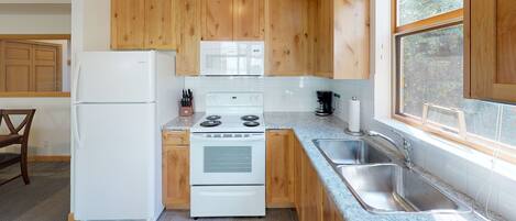 Une cuisine avec des meubles de rangement en bois, un réfrigérateur blanc, une cuisinière et un évier.