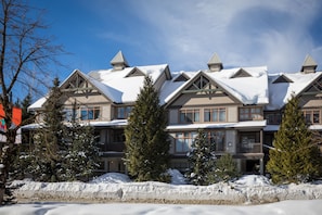 Un edificio grande de varios pisos con fachada simétrica, múltiples balcones y tejados cubiertos de nieve.