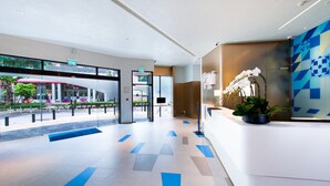 A modern hotel lobby with a reception desk, a large glass window, and a blue geometric floor pattern. - Holiday Inn Express Macau City Centre (Macau)