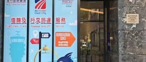 A building entrance with a sign for a check-in and baggage drop-off service, a flight check-in area, and a service area.