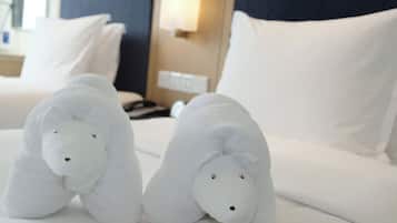A hotel room with a neatly made bed, a bedside table with a lamp, and a nightstand with a phone.