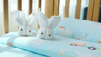 A child's bed with a light blue mattress and a pillow featuring cartoon cars and buildings.