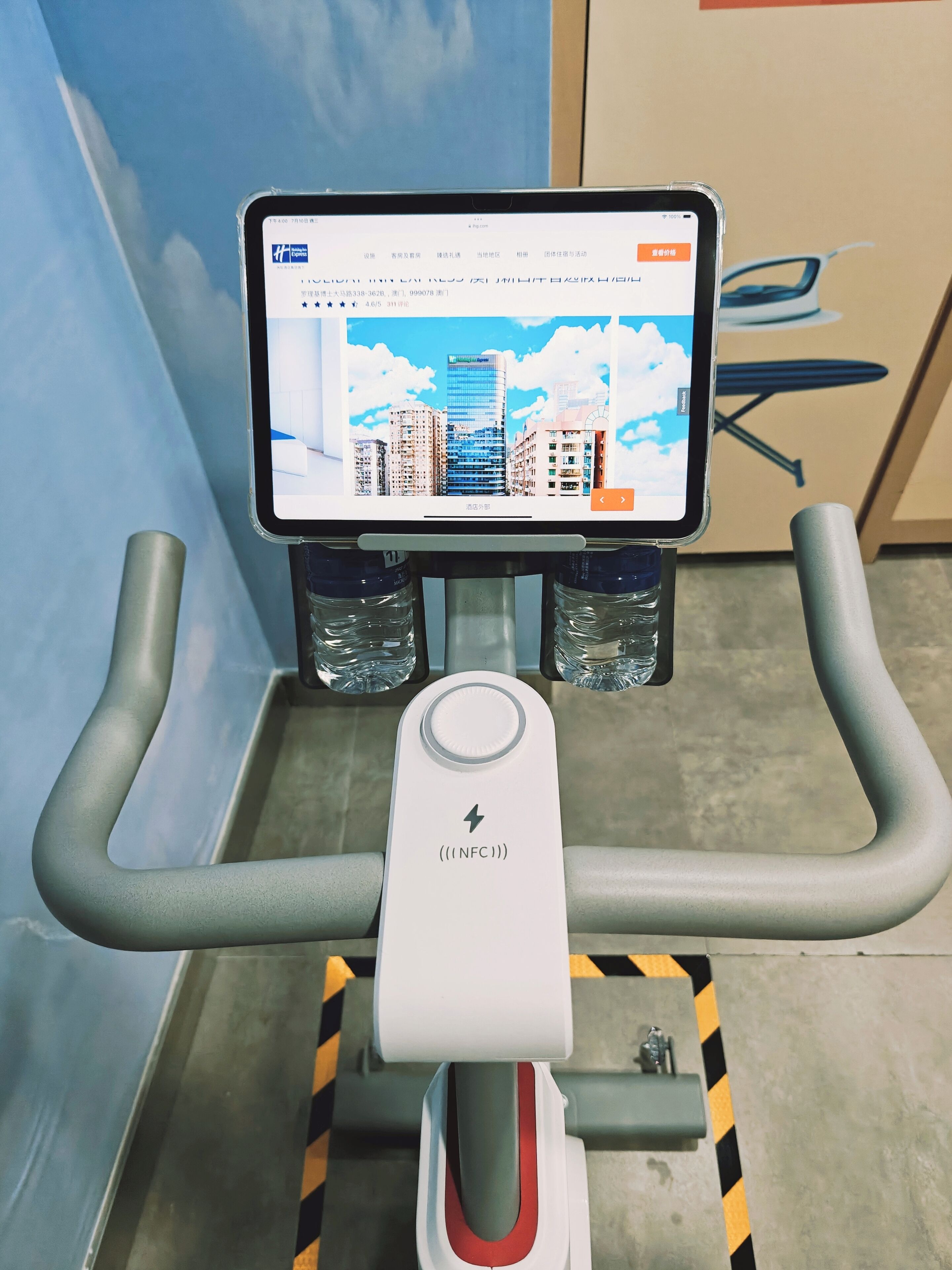 A treadmill with a digital display screen, water bottles, and a safety guard.