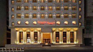 Ein mehrstöckiges Hotel mit einem markanten Eingang, beleuchteter Beschilderung und einer Reihe von Fenstern.