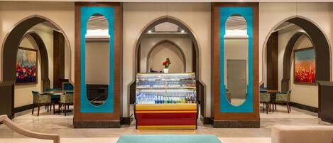 Un hall d’entrée avec un présentoir central de glaces, des espaces pour s’asseoir et des arches décoratives.