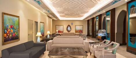 Un hall con un sofá, sillas, una mesa de centro y un techo decorativo.