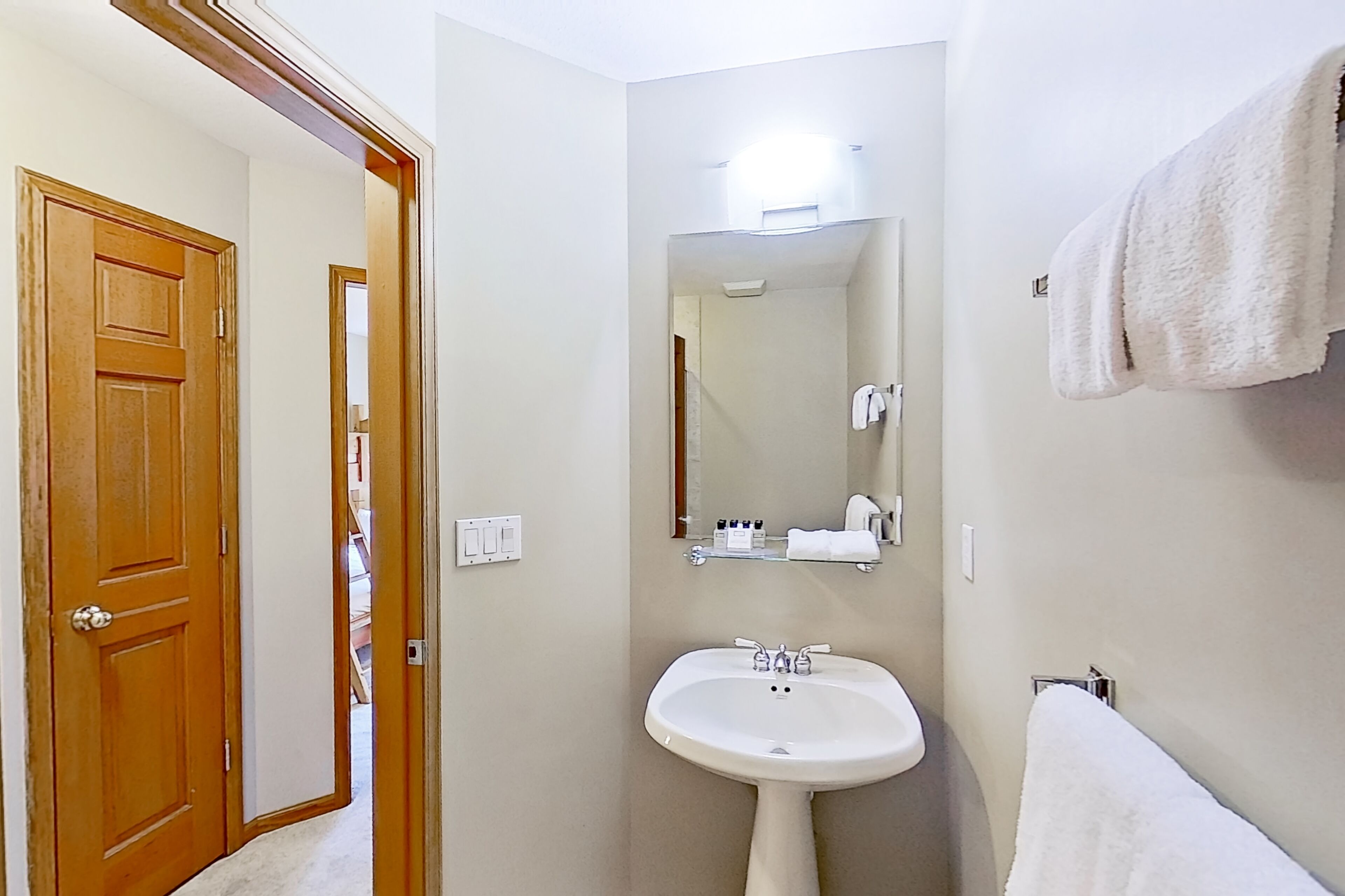 A bathroom with a white sink, a mirror, and a towel hanging on the wall.