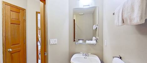 A bathroom with a white sink, a mirror, and a towel hanging on the wall.