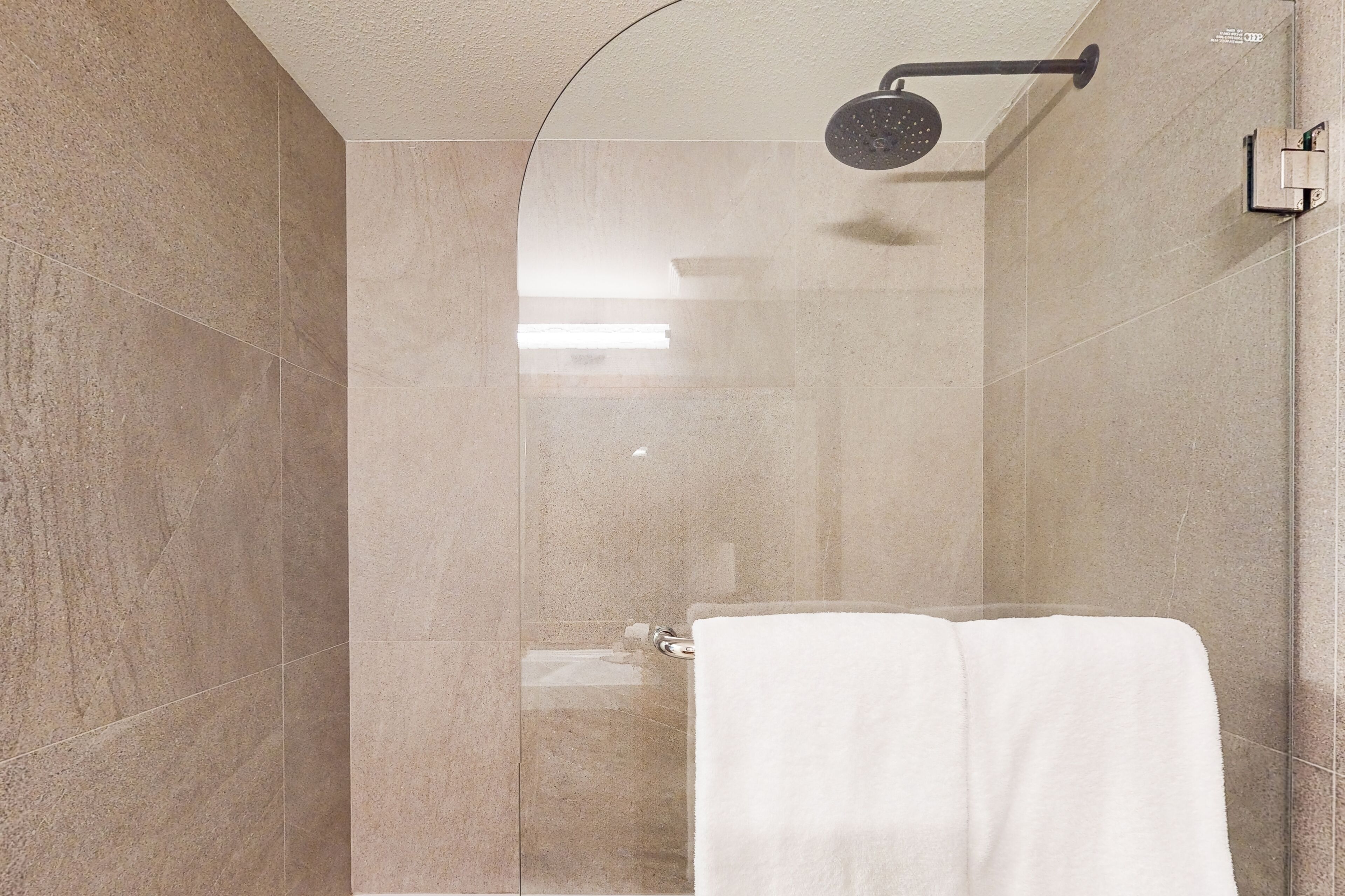 Un baño moderno con ducha de vidrio, una toalla blanca y un perchero de pared.