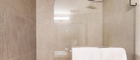 Un baño moderno con ducha de vidrio, una toalla blanca y un perchero de pared.
