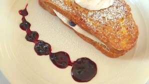 A plate with French toast, blueberries, whipped cream, and a berry sauce. - Chandler River Inn (Jonesboro)
