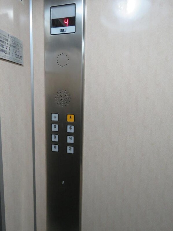 Panel de control de ascensor con pantalla digital mostrando el número 4 y un botón que dice 'SALE'.