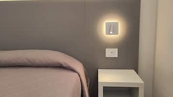 A bedroom with a bed, a bedside table, and a wall-mounted light fixture.