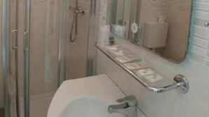 Un baño con ducha envuelta en vidrio, un lavabo y un espejo.