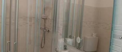 A bathroom with a glass-enclosed shower, a sink, and a mirror.