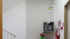 Un pasillo con un armario de madera, un jarrón con flores, un letrero de Wi-Fi y un extintor.