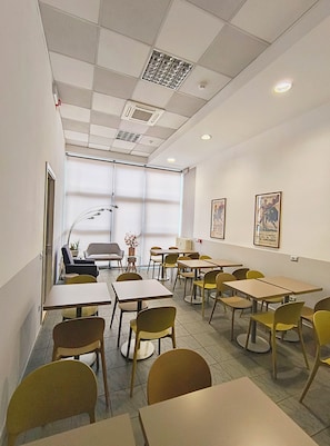 A conference room with tables and chairs, a large window, and a radiator. - Hotel Marta Forlì (Forlì)