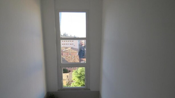 A narrow stairwell with a large window at the top, leading to a landing. - Hotel Marta Forlì (Forlì)