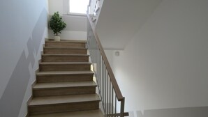 A staircase with a handrail, a potted plant, and a window at the top. - Hotel Marta Forlì (Forlì)