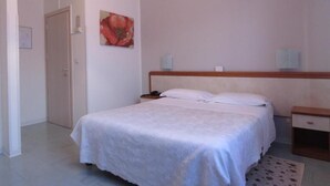 A bedroom with a bed, bedside tables, a nightstand, a door, and a wall-mounted artwork. - Hotel Marta Forlì (Forlì)
