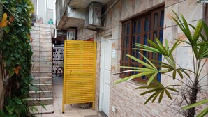 Une ruelle étroite, avec une porte jaune, un mur recouvert de carreaux et une fenêtre ornée de volets en bois.