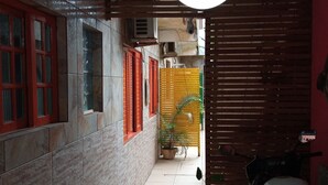 Un couloir étroit aux murs recouverts de carreaux, une plante en pot et un luminaire suspendu.