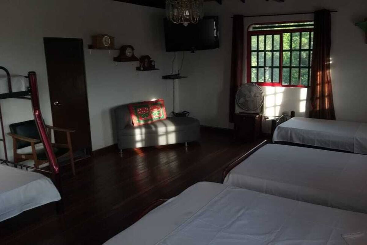 Habitación con dos camas, un escritorio, una silla, un televisor y una ventana con cortinas.