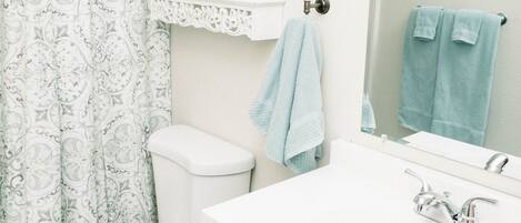 A bathroom with a toilet, sink, and shower curtain.