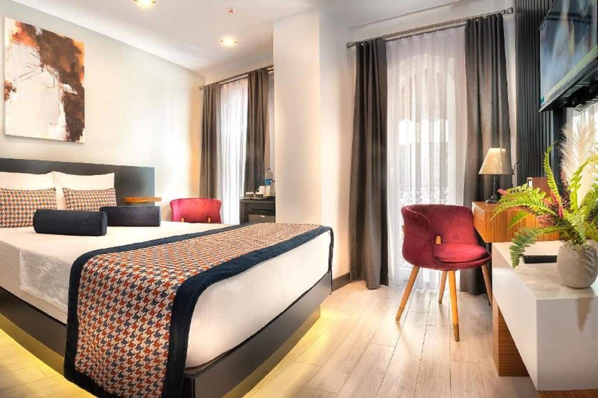 A modern hotel room with a large bed, a desk, and a TV.