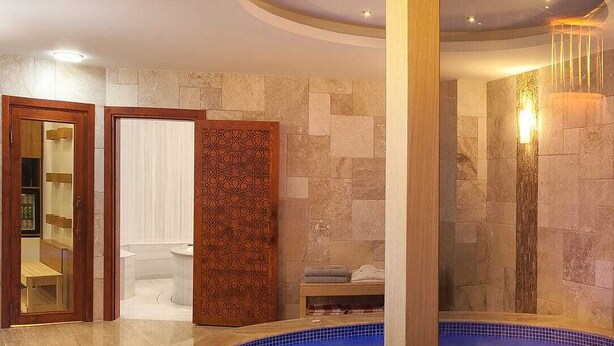 A spa area with a circular hot tub, stone walls, and a wooden door. - Ooda Rooms Kadıköy (Istanbul)