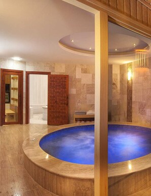 A spa area with a circular hot tub, stone walls, and a wooden door. - Ooda Rooms Kadıköy (Istanbul)