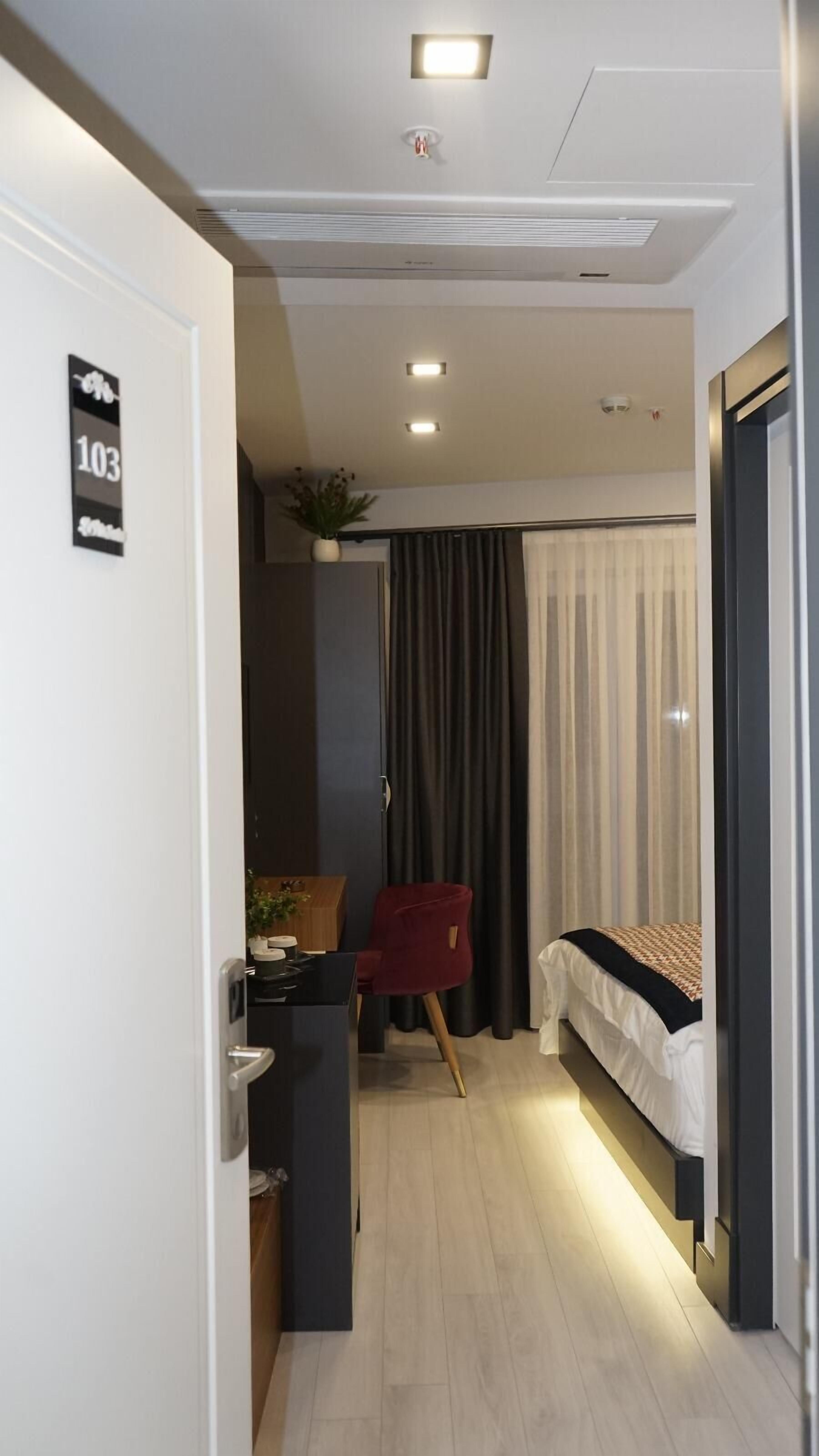 Ein kleines Hotelzimmer mit einem Bett, einem Schreibtisch und einem Stuhl.