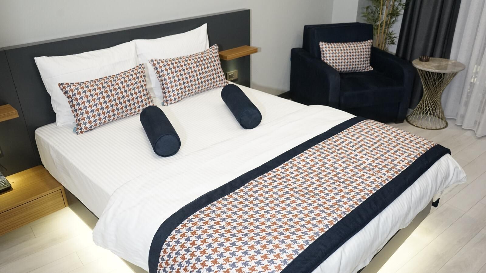 A neatly made bed with a patterned bedspread, two pillows, and a matching throw blanket.