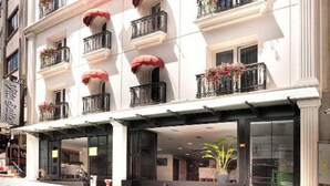 Ein mehrstöckiges Hotel mit Balkonen, die mit Blumen geschmückt sind, großen Fenstern und klassischer Architektur.