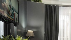 A modern living room with a dark grey partition, a red velvet chair, a wooden side table with a lamp, and potted plants. - Ooda Rooms Kadıköy (Istanbul)
